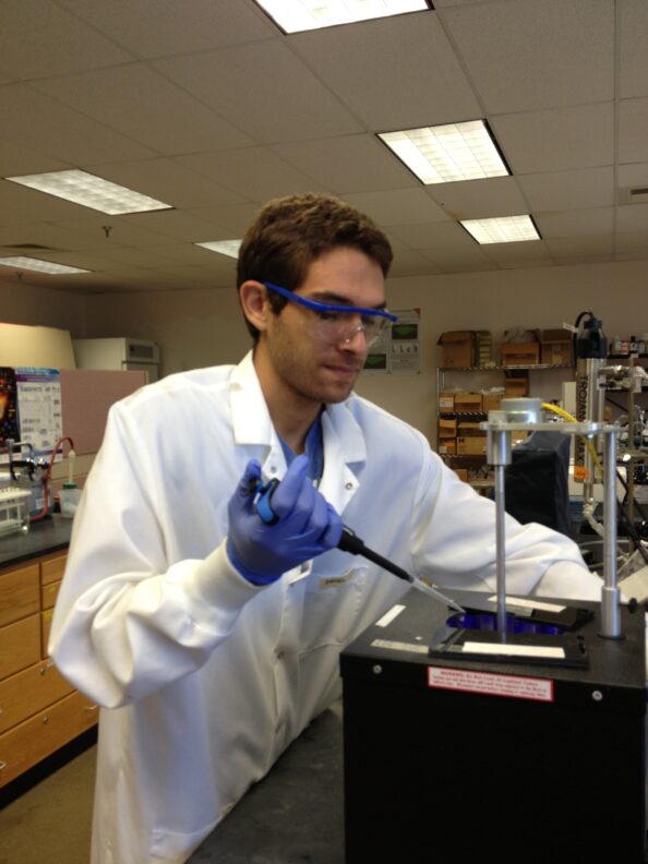 Daniel Ocasio collects a sample from a photo-reactor being used to degrade antibiotics in wastewater